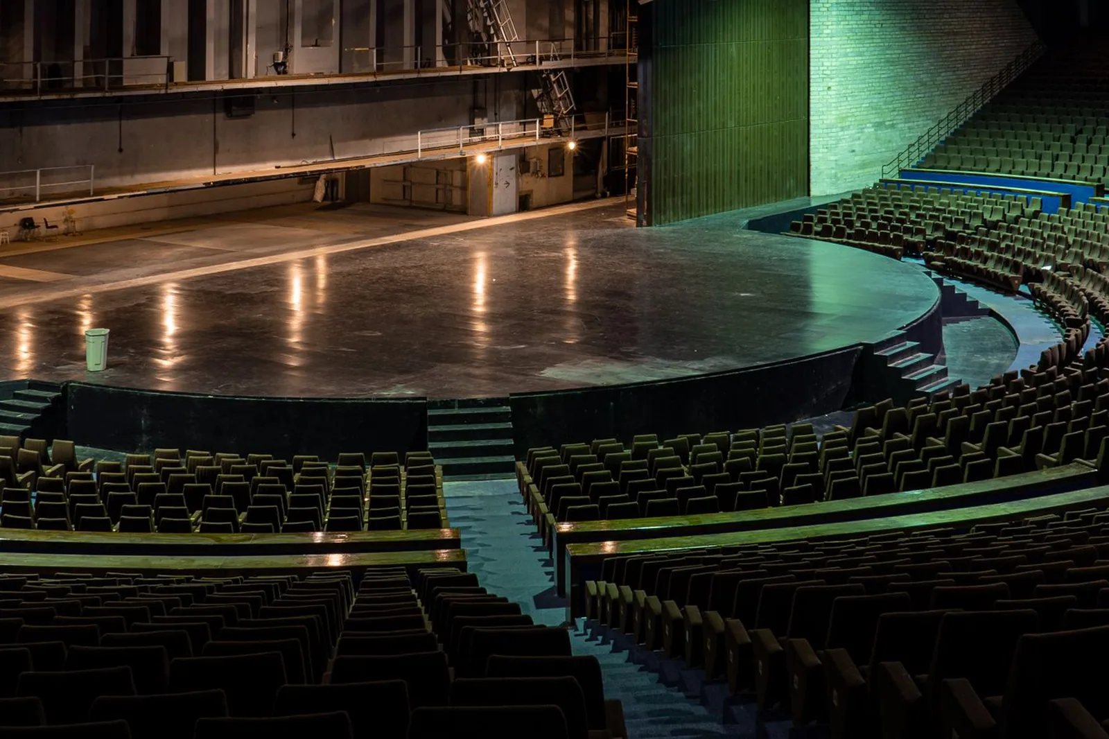 Palco de teatro vazio com poltronas em curva e iluminação verde