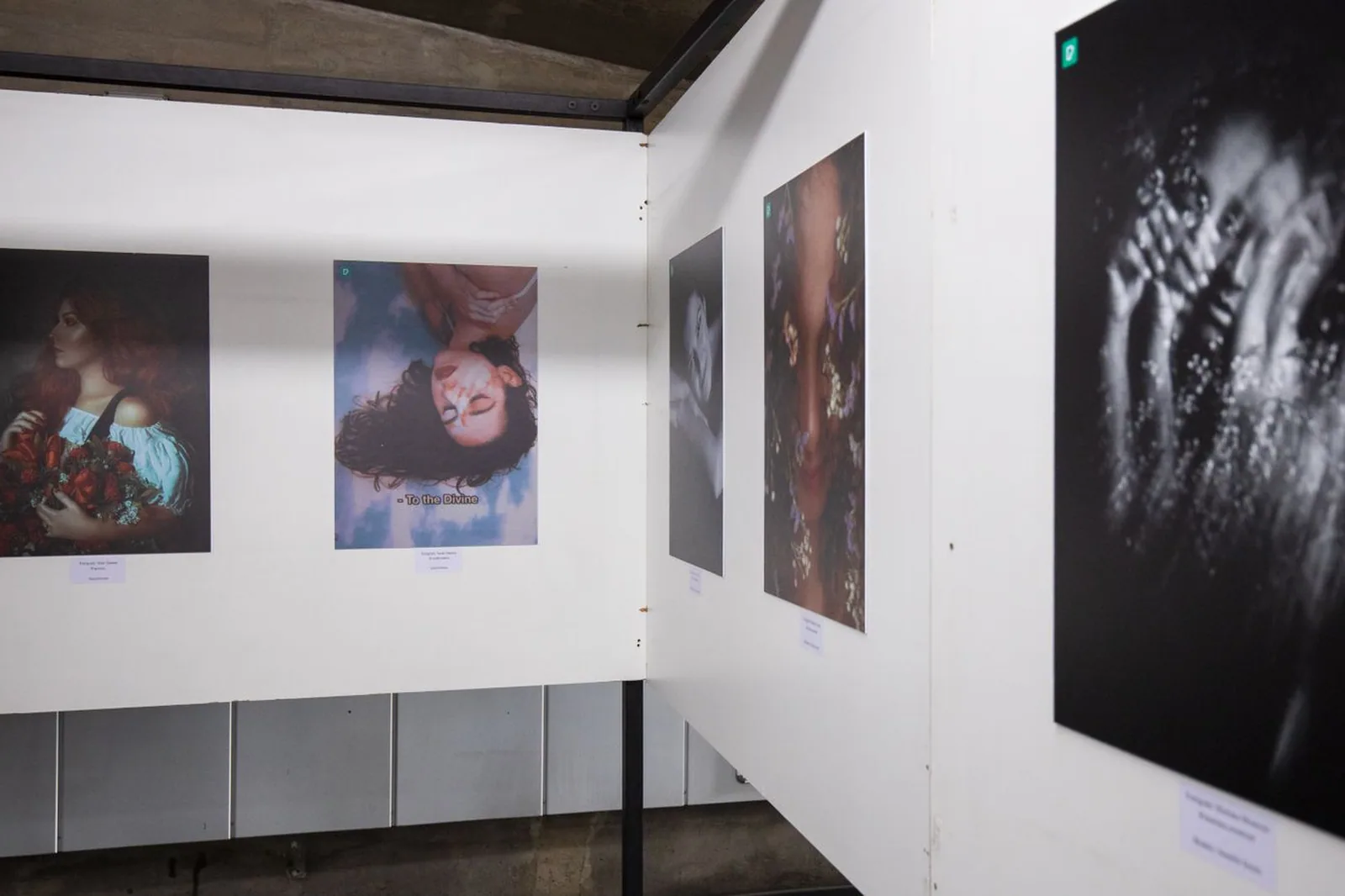 Sala de exposição fotográfica com fotos em preto e branco e coloridas penduradas nas paredes