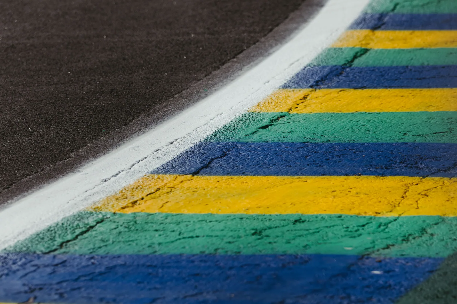 Zebra de pista de corrida pintada em verde, amarelo e azul, ao lado do asfalto